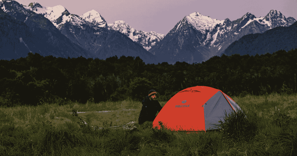 eric using a marmot tent in front of a mountain landscape backpacking and hiking
