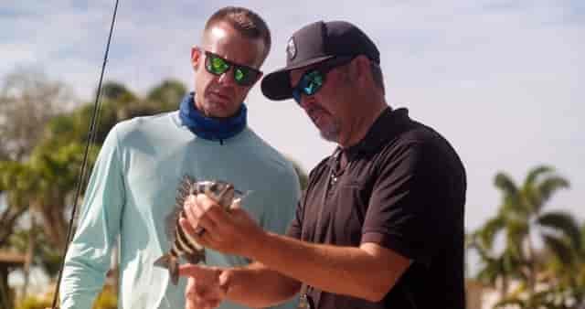 Captain Chris pointing out the sharp barbs on a Convict Fish to Chef Corso